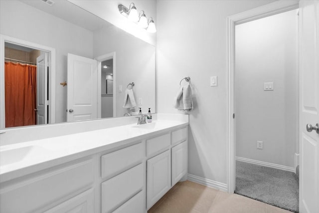 bathroom featuring baseboards, double vanity, tile patterned floors, and a sink