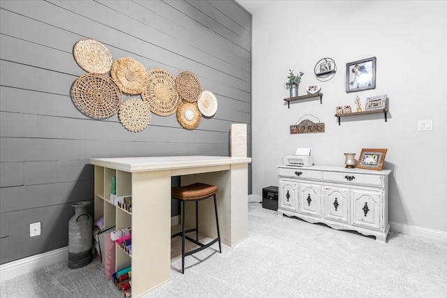 home office with wooden walls, baseboards, and light carpet