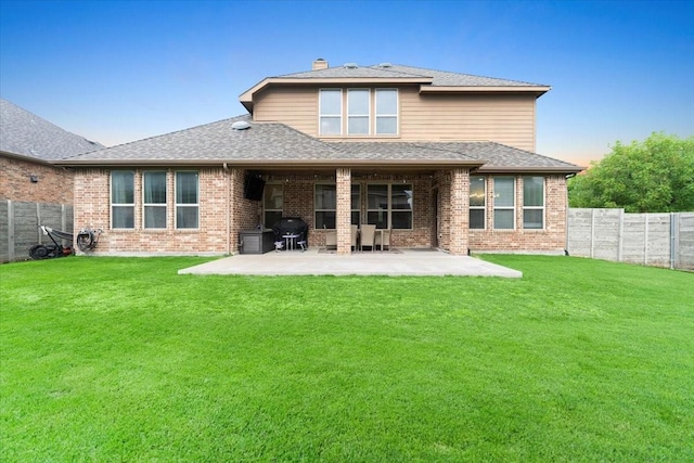 rear view of property featuring brick siding, a fenced backyard, and a patio area