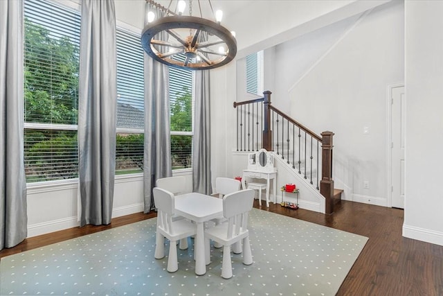 dining room featuring a healthy amount of sunlight, baseboards, wood finished floors, and a notable chandelier