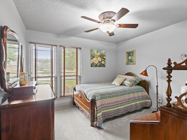 bedroom featuring baseboards, light carpet, a ceiling fan, and a textured ceiling