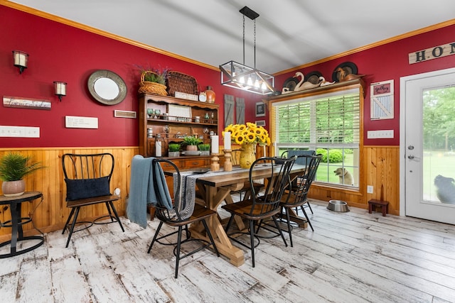 dining area with wainscoting, a chandelier, wood walls, wood finished floors, and ornamental molding