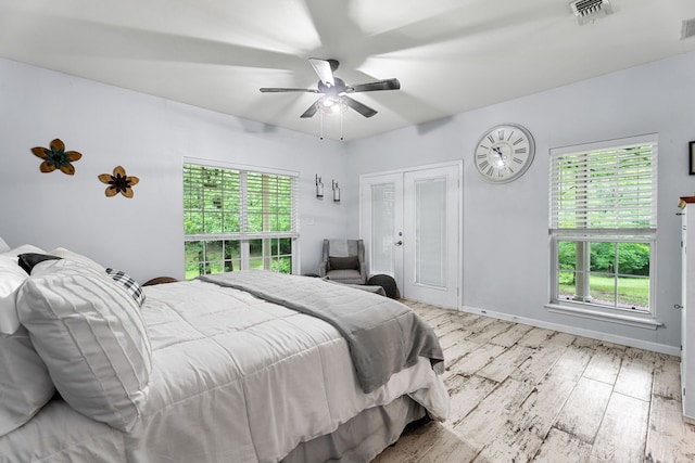 bedroom with a ceiling fan, visible vents, french doors, and wood finished floors