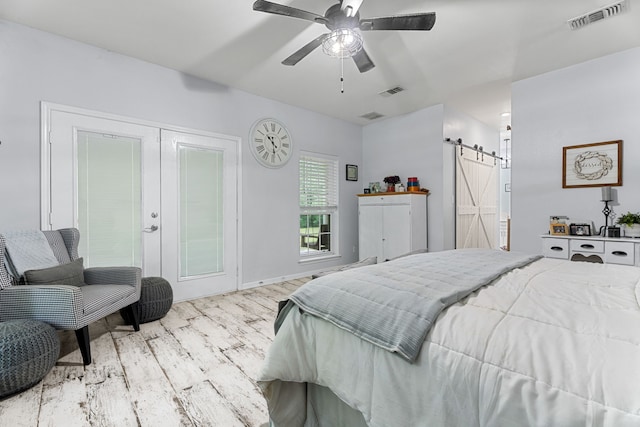 bedroom featuring visible vents, a barn door, wood finished floors, and french doors