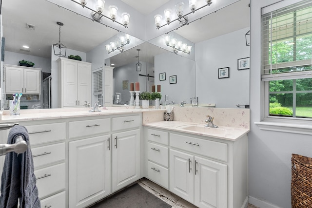 bathroom featuring a sink, baseboards, double vanity, and visible vents