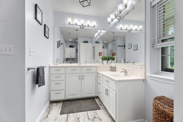 full bathroom with baseboards, a sink, and two vanities