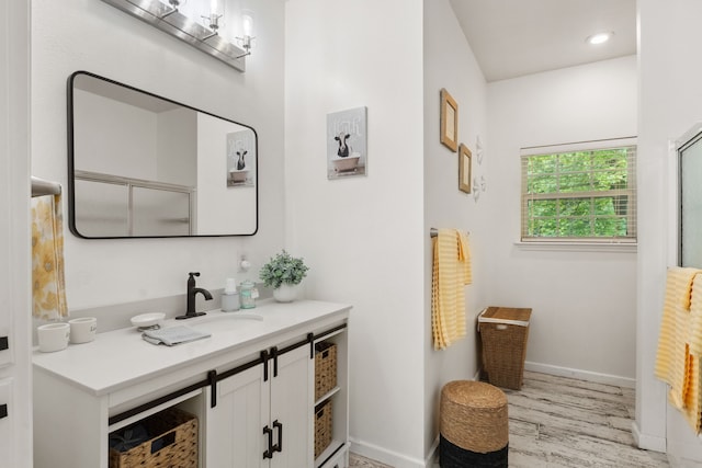 bathroom featuring an enclosed shower, baseboards, wood finished floors, and vanity