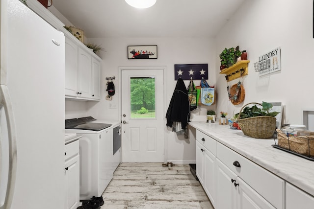 laundry area with light wood-style floors, cabinet space, and washing machine and clothes dryer