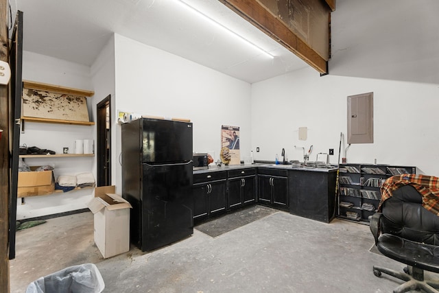 kitchen featuring electric panel, concrete flooring, a sink, freestanding refrigerator, and dark cabinetry