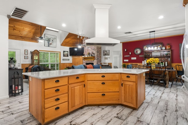 kitchen featuring ceiling fan, light wood-style floors, light countertops, a brick fireplace, and open floor plan