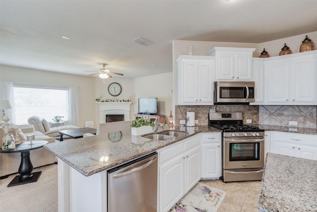 kitchen featuring a sink, stainless steel appliances, open floor plan, a peninsula, and visible vents