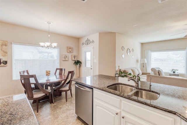 kitchen featuring an inviting chandelier, dark stone counters, a sink, dishwasher, and hanging light fixtures