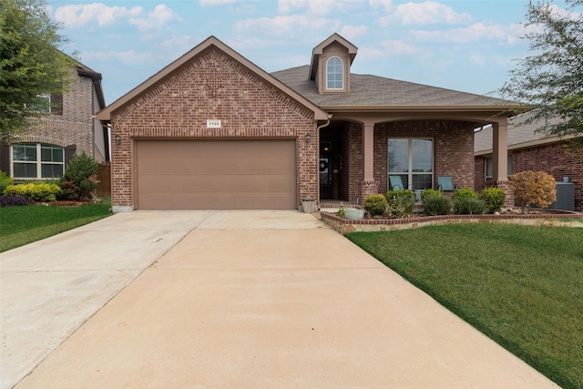 view of front facade featuring roof with shingles, an attached garage, brick siding, a front yard, and concrete driveway