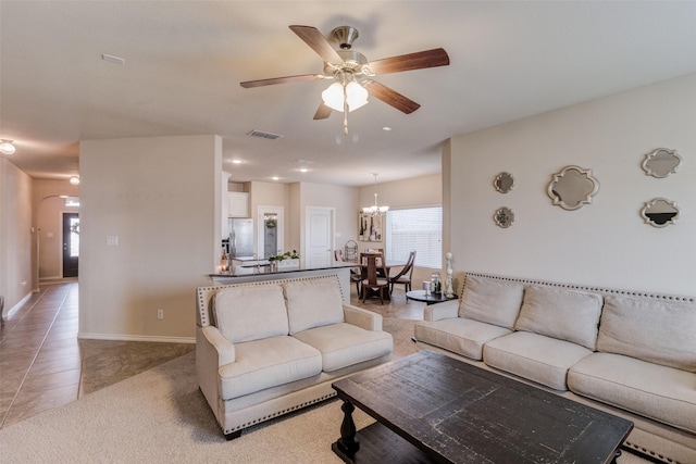 living room featuring visible vents, light tile patterned flooring, baseboards, arched walkways, and ceiling fan with notable chandelier