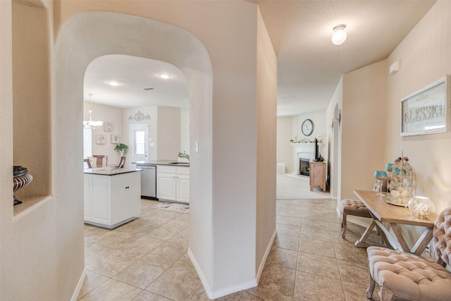 hallway featuring arched walkways, baseboards, and light tile patterned flooring