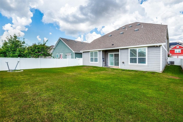 back of house with a fenced backyard, roof with shingles, a yard, and central AC unit