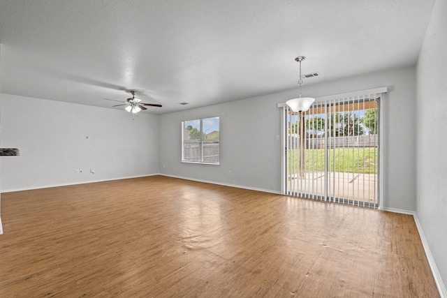 interior space featuring baseboards, ceiling fan, wood finished floors, and visible vents