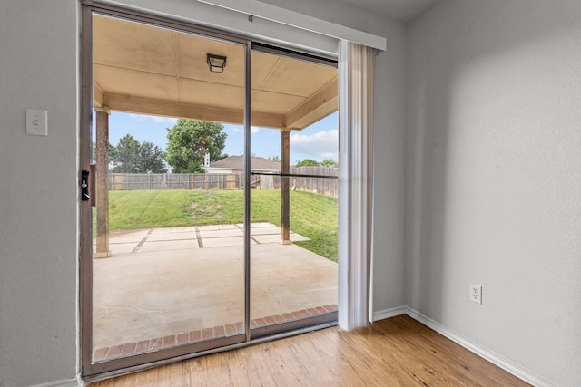 doorway to outside featuring baseboards and wood finished floors