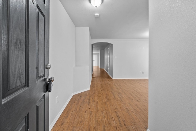 foyer with baseboards, arched walkways, and wood finished floors