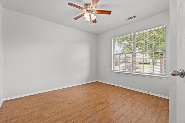 spare room with ceiling fan, visible vents, vaulted ceiling, wood finished floors, and baseboards