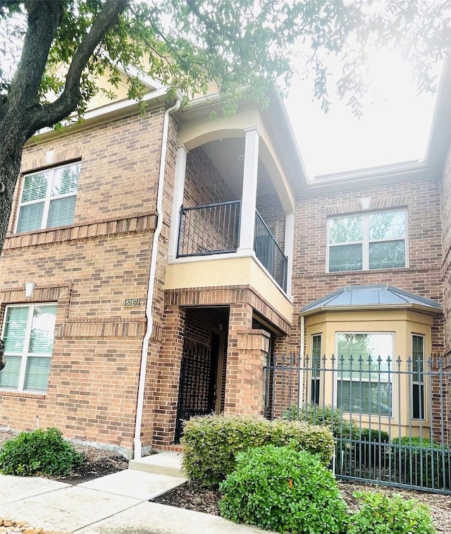 view of side of home with brick siding and a balcony