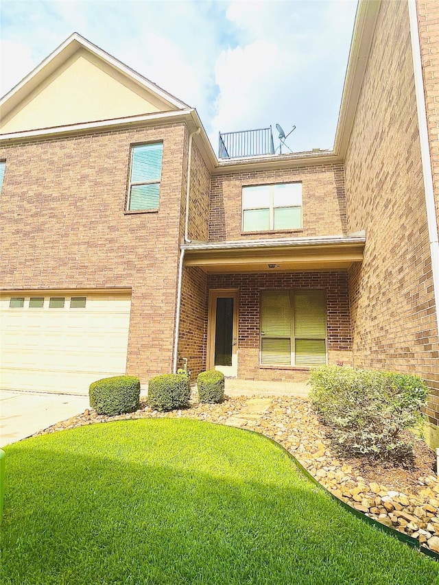 traditional home featuring concrete driveway, brick siding, an attached garage, and a front yard