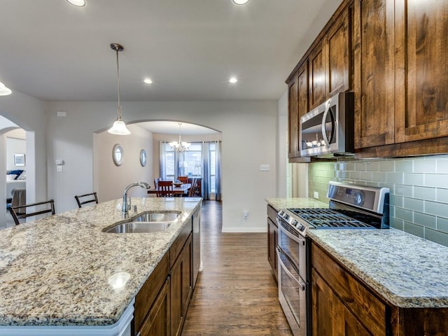5517 Grove Cove Dr, Mckinney, TX 75071 - kitchen with dark wood-style floors, arched walkways, a sink, backsplash, and stainless steel appliances