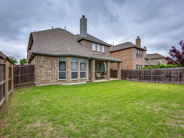 5517 Grove Cove Dr, Mckinney, TX 75071 - rear view of property featuring brick siding, a fenced backyard, a chimney, a patio, and a yard