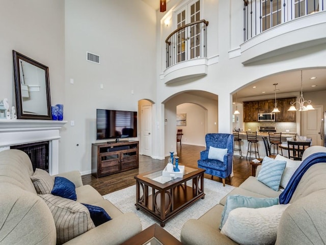 5517 Grove Cove Dr, Mckinney, TX 75071 - living room with visible vents, a towering ceiling, arched walkways, wood finished floors, and baseboards