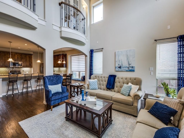 5517 Grove Cove Dr, Mckinney, TX 75071 - living room featuring an inviting chandelier, arched walkways, a high ceiling, and wood finished floors