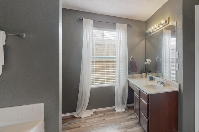 bathroom featuring vanity, baseboards, a textured ceiling, and wood finished floors