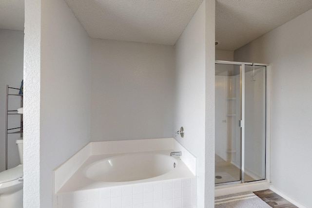 full bath featuring a garden tub, a textured ceiling, a stall shower, wood finished floors, and toilet