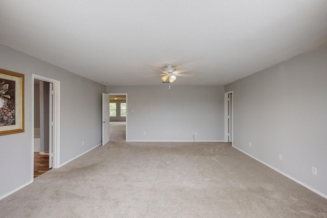 carpeted spare room with baseboards and a ceiling fan