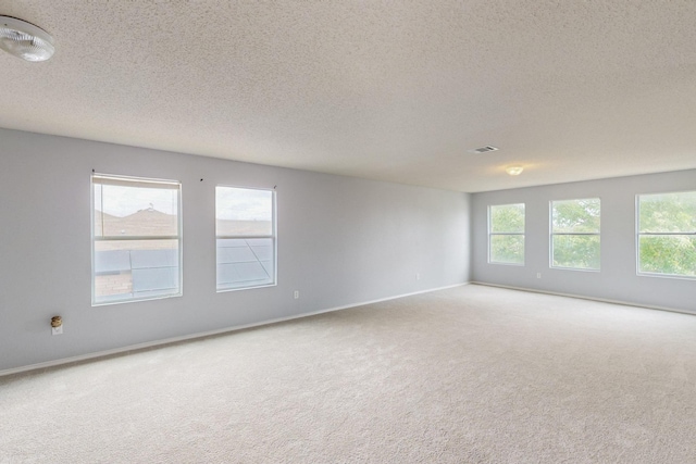 carpeted spare room featuring baseboards, a textured ceiling, and visible vents