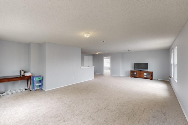 unfurnished living room with a textured ceiling, baseboards, and carpet
