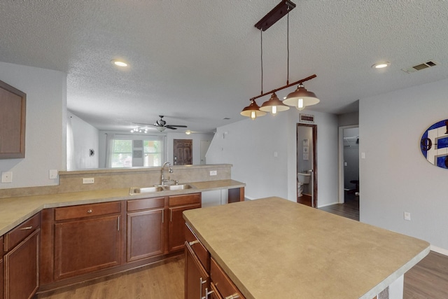 kitchen with ceiling fan, a sink, light wood-style floors, a textured ceiling, and visible vents