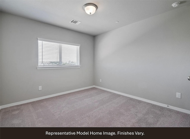carpeted spare room featuring baseboards and visible vents