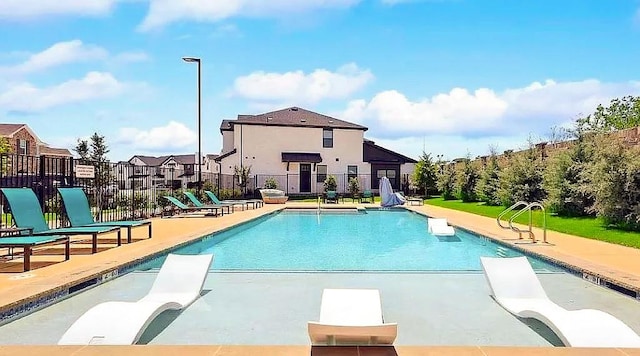 community pool featuring fence, a patio area, and a residential view