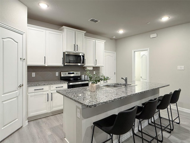 kitchen with a sink, stainless steel appliances, light wood-style flooring, and visible vents