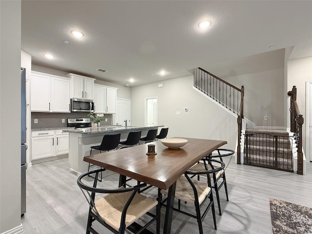 dining room with visible vents, recessed lighting, stairs, and light wood-type flooring