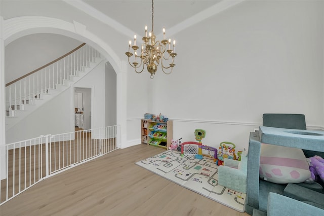 playroom with wood finished floors, arched walkways, and a chandelier