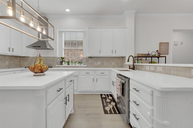 kitchen with a sink, stainless steel dishwasher, crown molding, a peninsula, and tasteful backsplash
