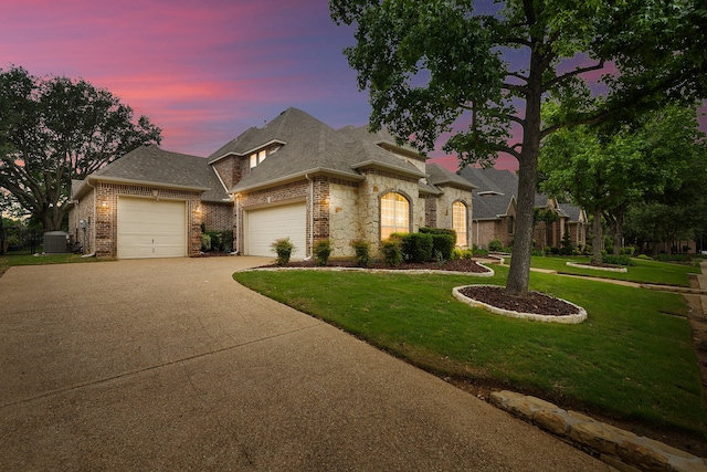 french provincial home featuring an attached garage, roof with shingles, central air condition unit, brick siding, and driveway