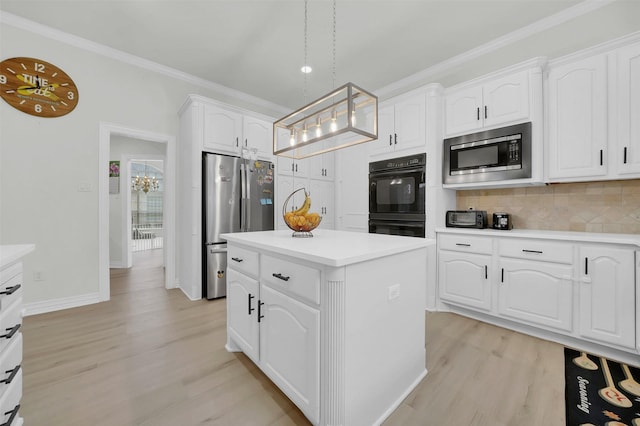 kitchen featuring appliances with stainless steel finishes, light wood finished floors, a kitchen island, decorative backsplash, and white cabinetry