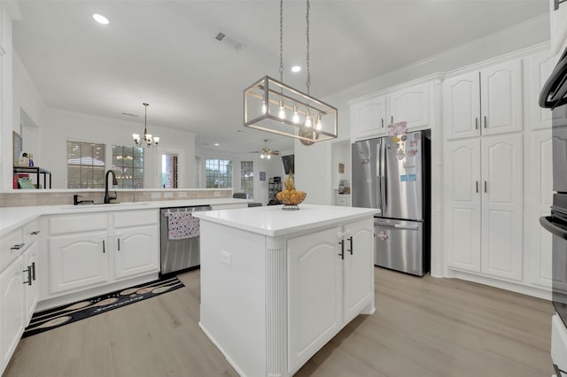 kitchen featuring appliances with stainless steel finishes, a sink, a chandelier, light wood-style flooring, and a center island