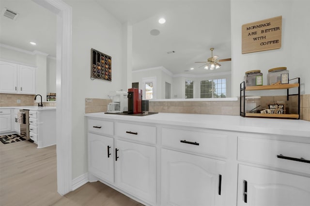 kitchen featuring decorative backsplash, ornamental molding, a ceiling fan, light wood-style floors, and light countertops