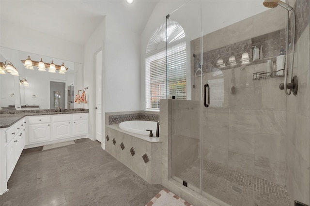 bathroom with a shower stall, vanity, a bath, and vaulted ceiling