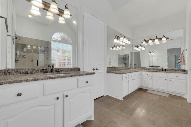 full bath with a shower stall, a chandelier, and two vanities