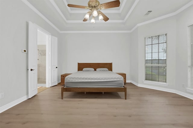 bedroom with a tray ceiling, light wood-type flooring, ceiling fan, ensuite bath, and baseboards