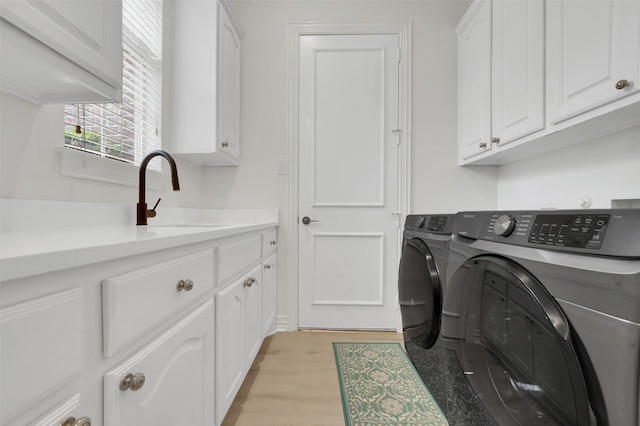 laundry area with washer and clothes dryer, cabinet space, and light wood-style flooring